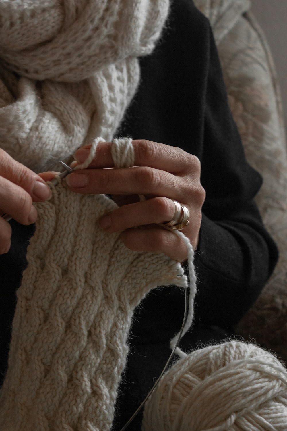 Hands working soft yarn with a crochet hook in a warm creative setting