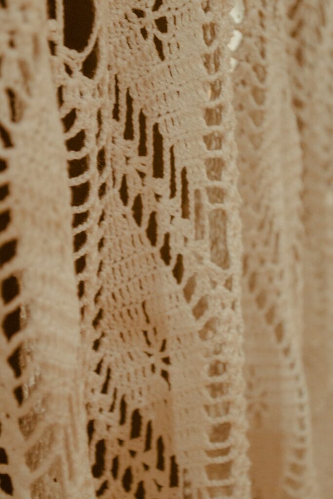 Close-up of cream crochet lace with delicate geometric shell texture