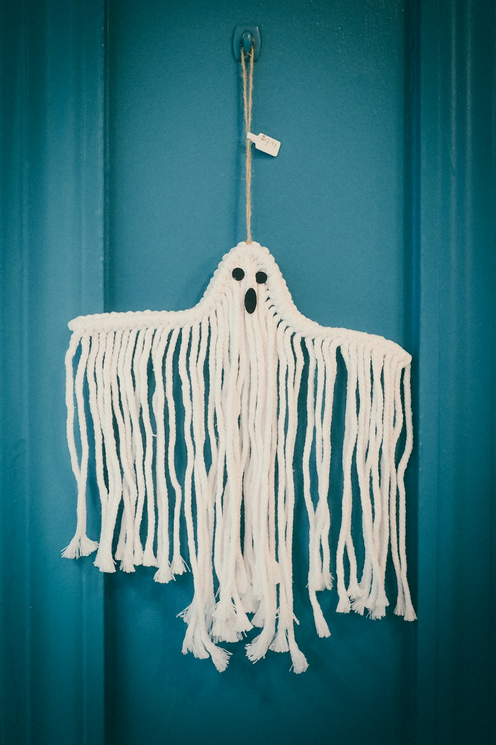 Small white ghost decoration displayed against a soft muted background